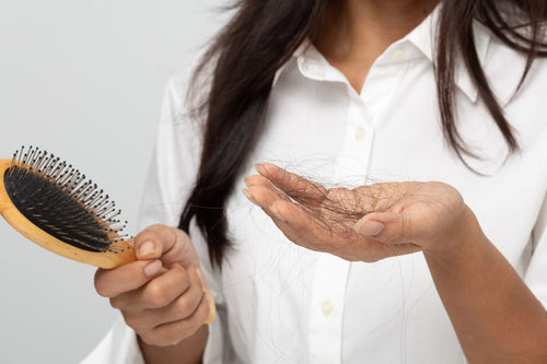 woman holding brush and hand full of hairs
