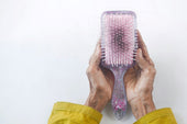 hands holding comb full of hair from hormonal hair loss