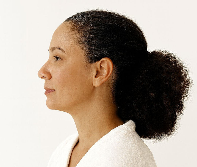 Multiracial midlife woman in profile illustrating stress-protective scalp care.