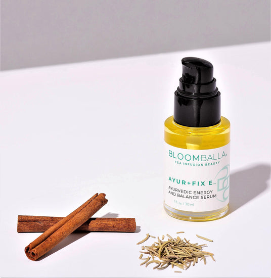 bottle of ayurvedic scalp serum next to ayurvedic herbs